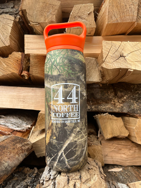 Camouflage canister with orange handle on a pile of wood with 44 North Coffee logo