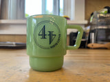 A jade green ceramic coffee mug with a black printed logo reading '44 NORTH COFFEE' sits on a wooden countertop.